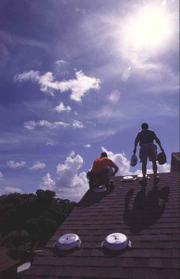 Two researchers instrumenting the roof of a house