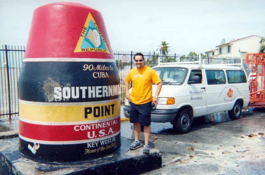 Luis Aponte standing next to the Southernmost point marker in the Keys